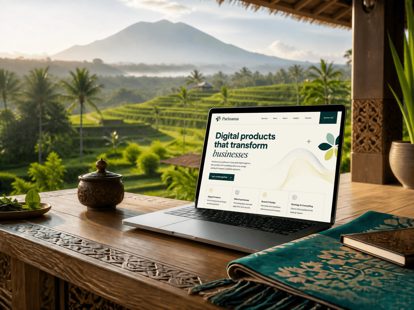 Laptop displaying the Parinama Kreatif website in a creative workspace overlooking Bali
